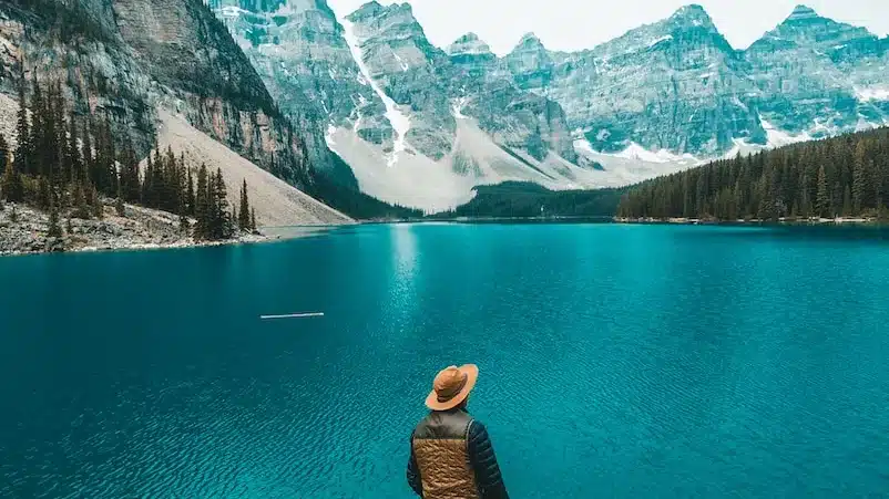 man standing on rock near lake