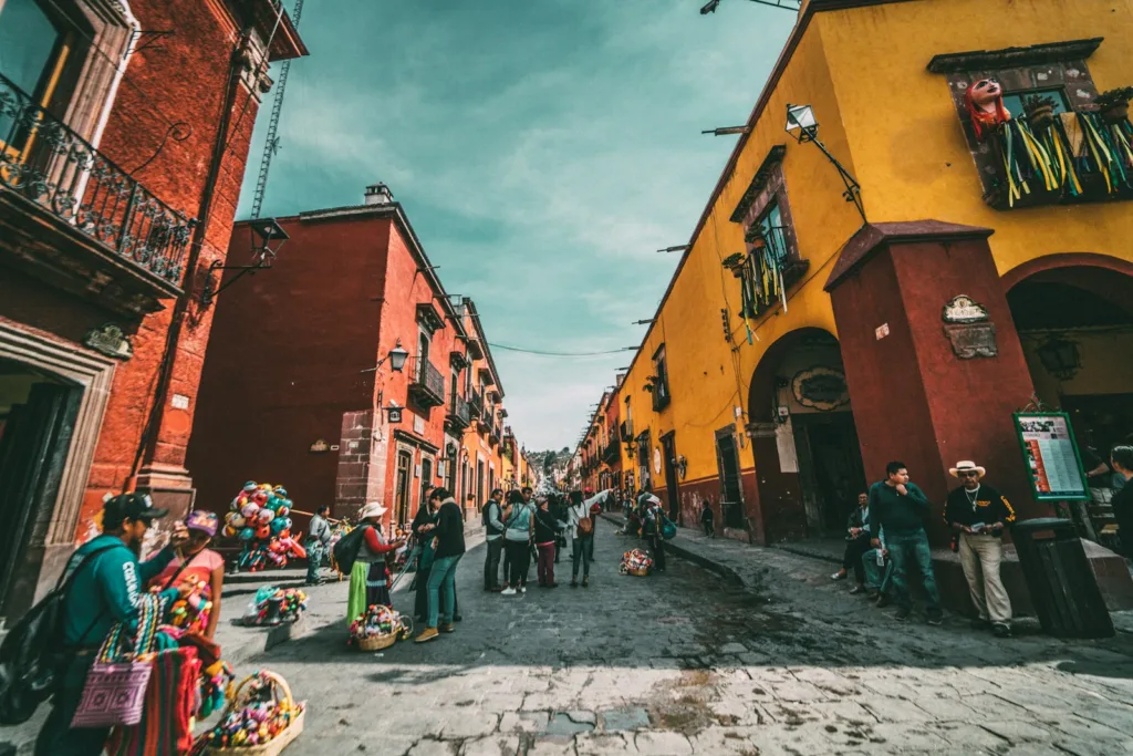 Mexico people standing on corner road near concrete buildings during daytime